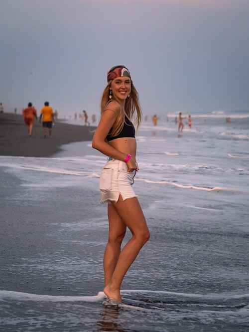 Me standing in shallow water on the black sand beach of El Paredon in Guatemala