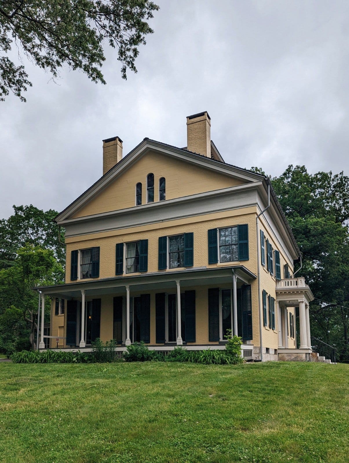 Exterior of the Emily Dickinson Museum - a yellow house with dark green shutters