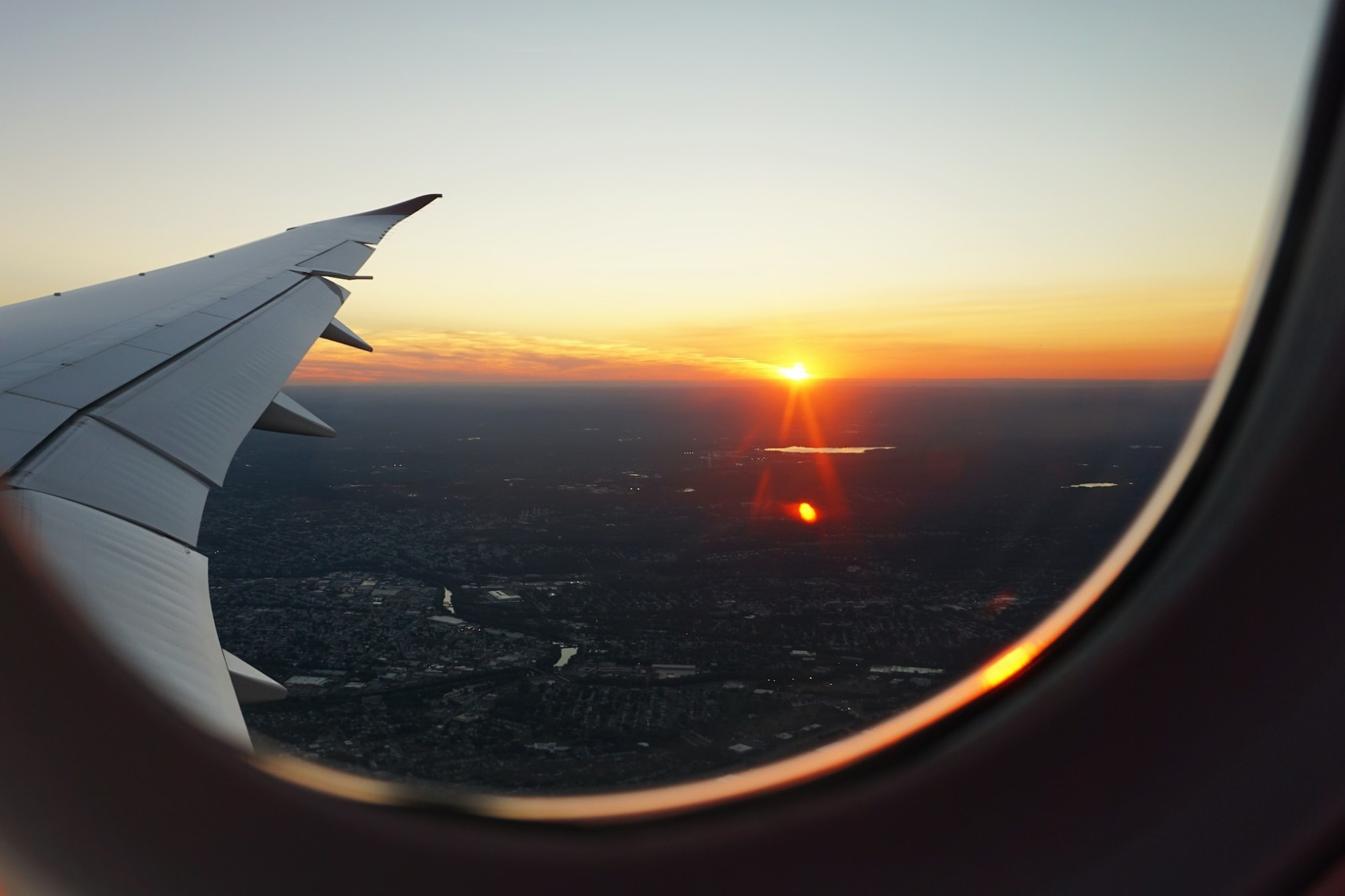 Airport staff assisting passengers and a view of an airplane taking off at sunset from a window seat