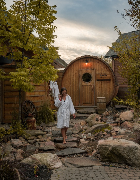 Solo female traveler walking across large stones in front of a wooden building in Quebec