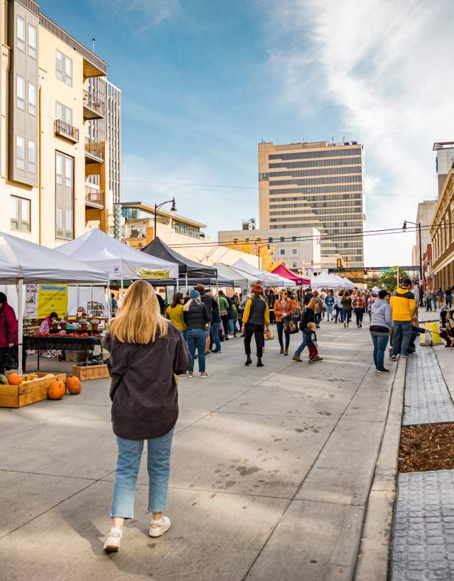 blonde women walking through a market with vendors in white tents