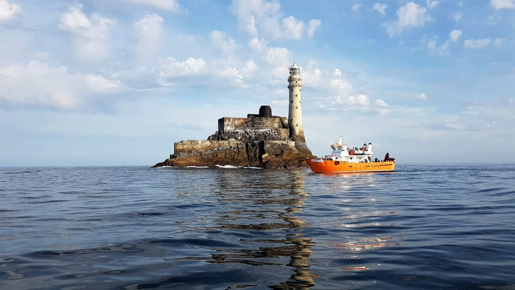 A coastal community benefiting from tourism, with local businesses thriving due to the influx of visitors attracted by a nearby lighthouse