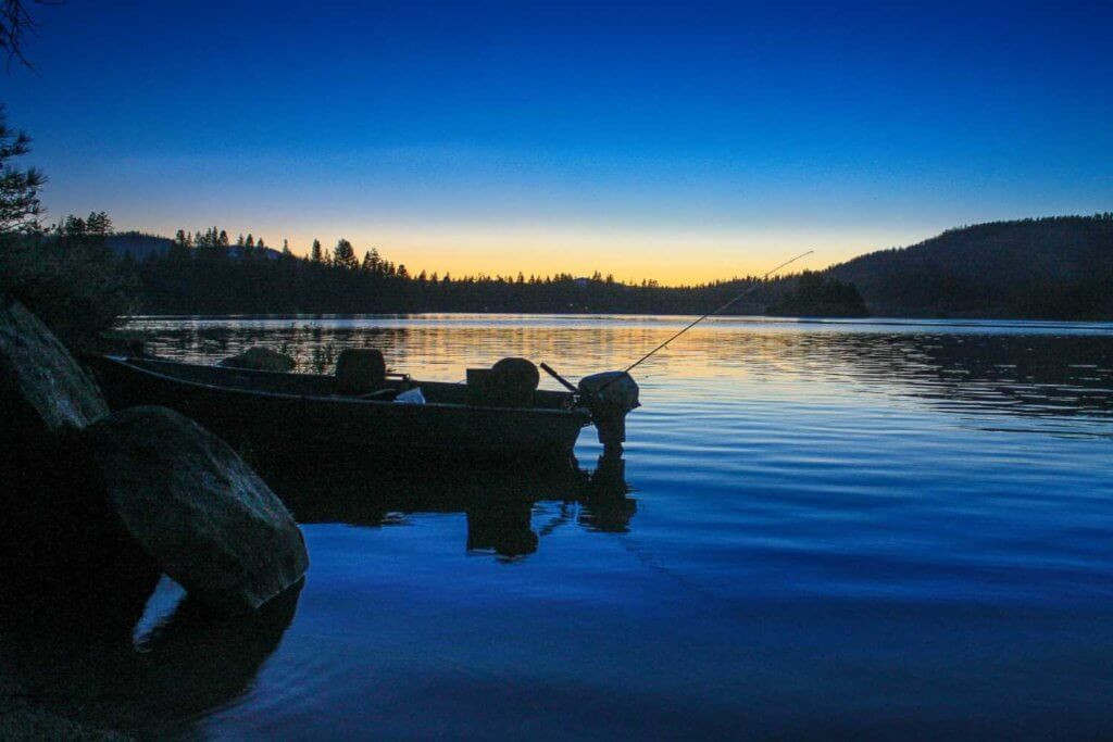Antelope Lake at sunset, with a silhouette of a fisherman casting their line into the still waters