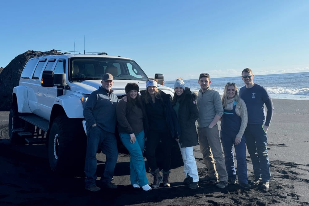 A family enjoying a monster truck ride on a black beach in Iceland, showcasing the adventure and unique landscapes.