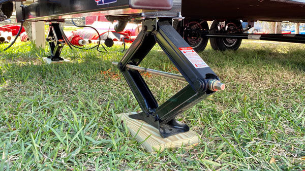 A travel trailer with scissor jacks on the rear.