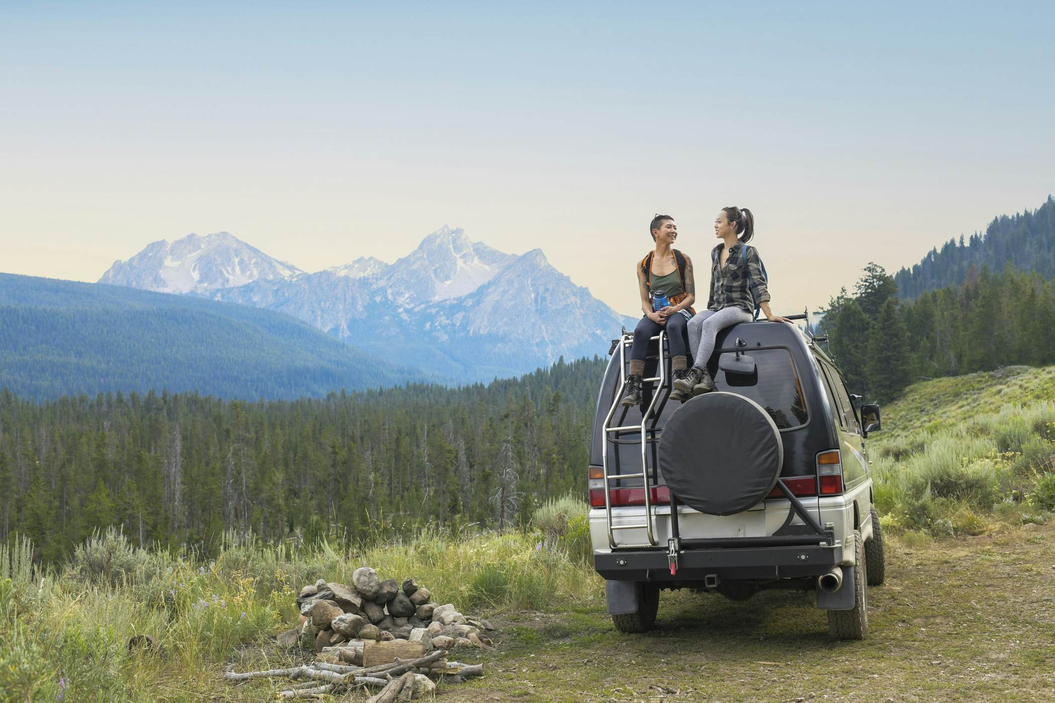 Two women sitting on top of a four-wheel drive vehicle in a mountainous region