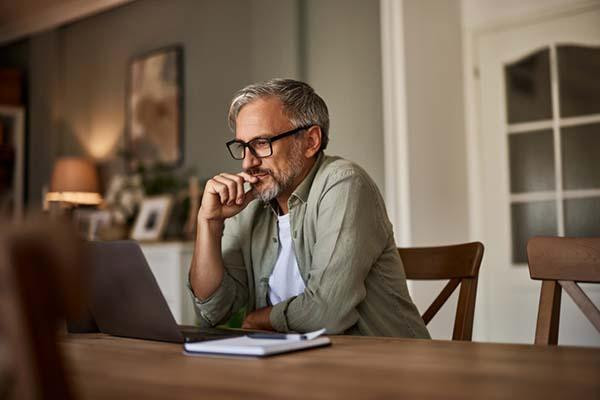 Man sitting at desk with laptop and medication