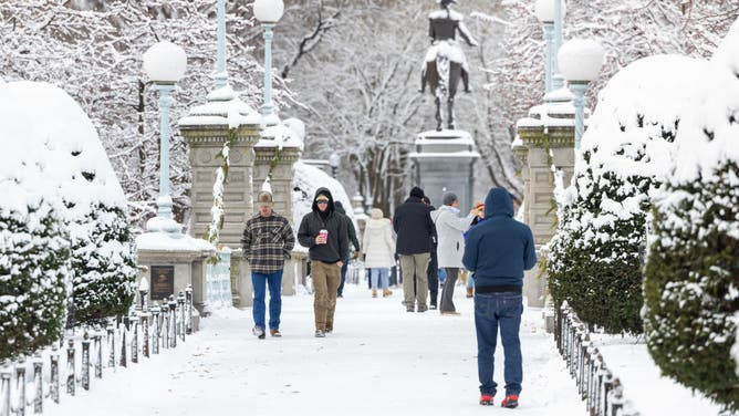People walking through the snow in Boston Public Garden in December