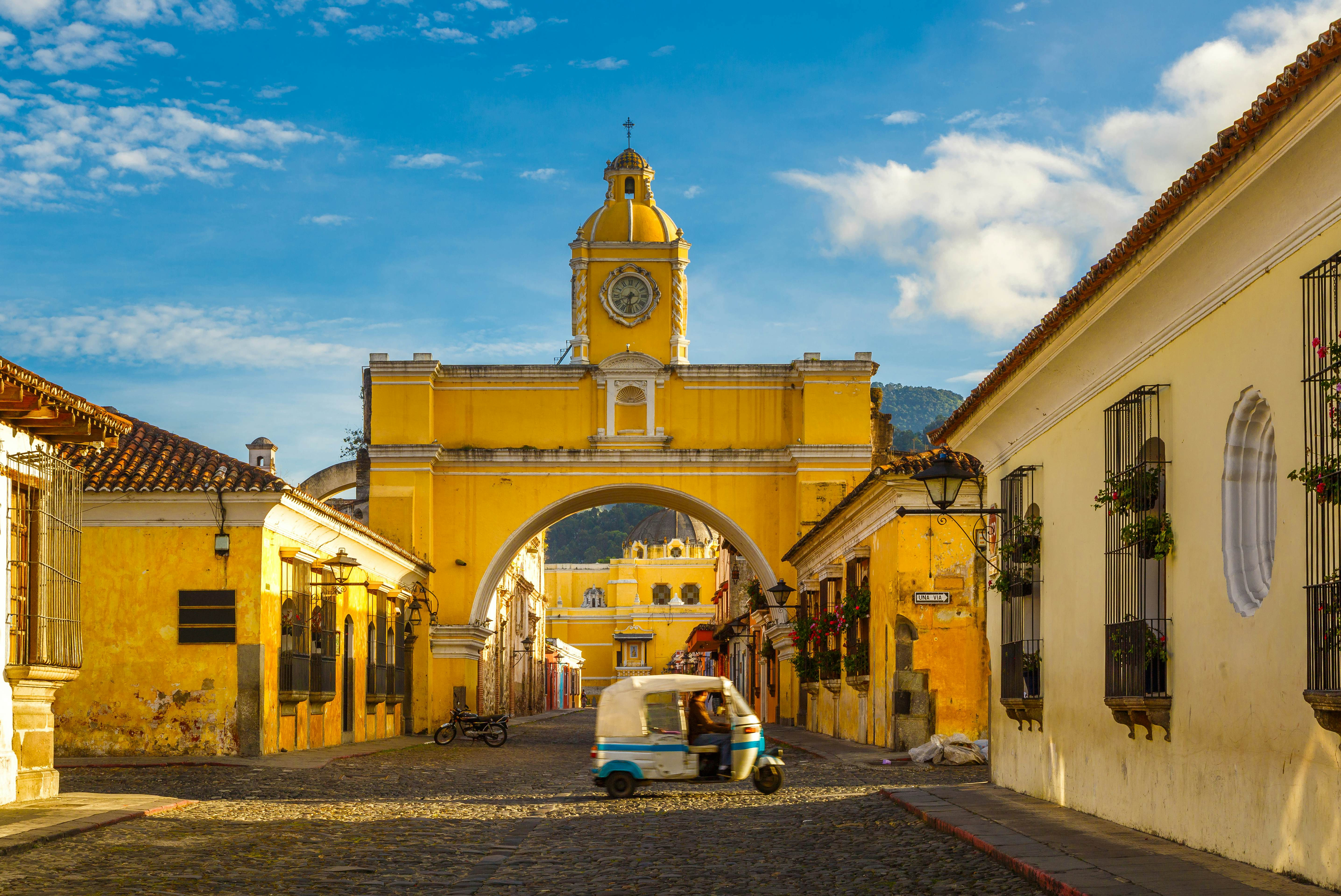 A tuk-tuk passing through the Arch of Santa Catalina in Antigua, Guatemala