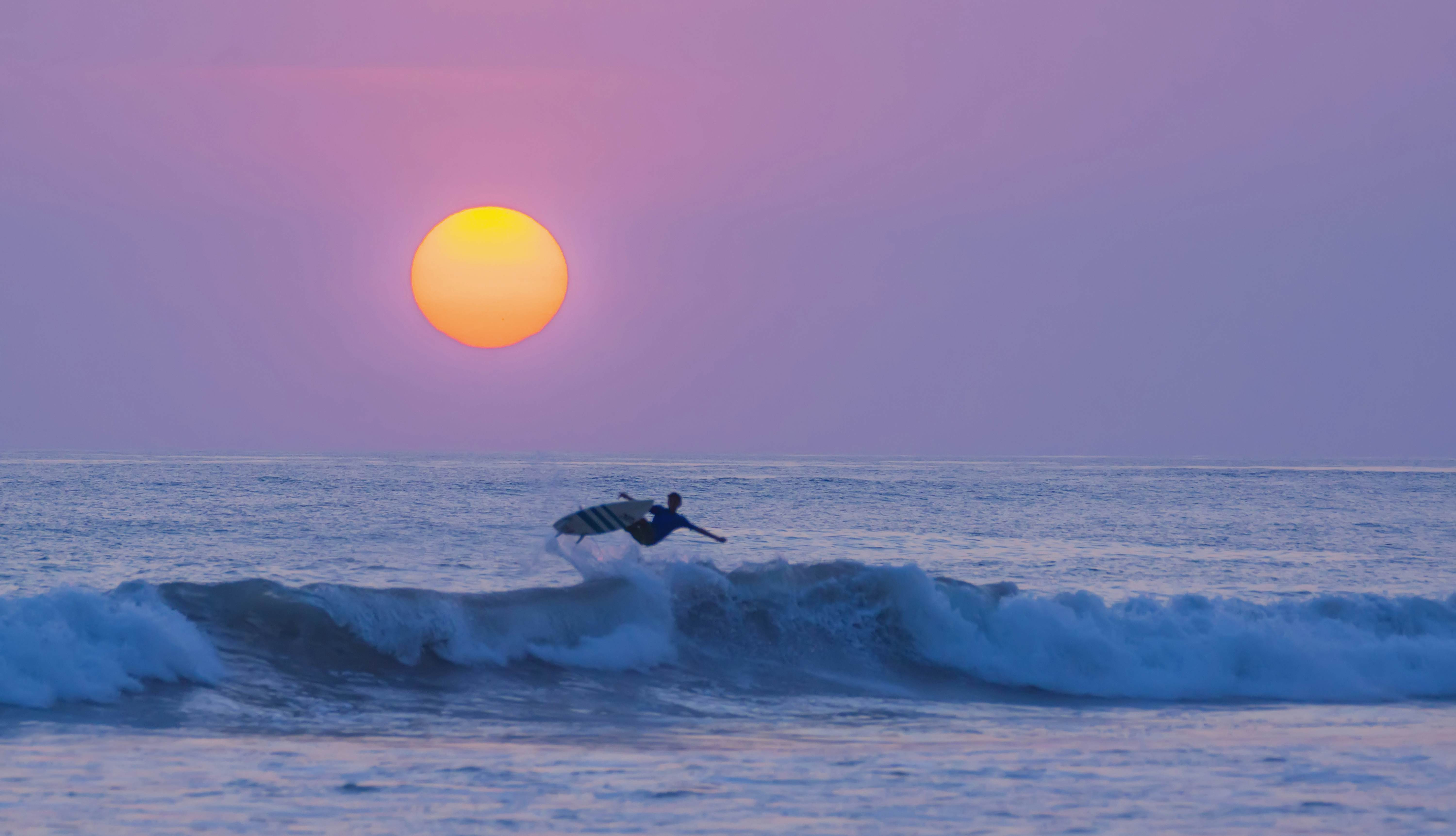 Surfer in front of the setting sun at Playa Carmen in Costa Rica