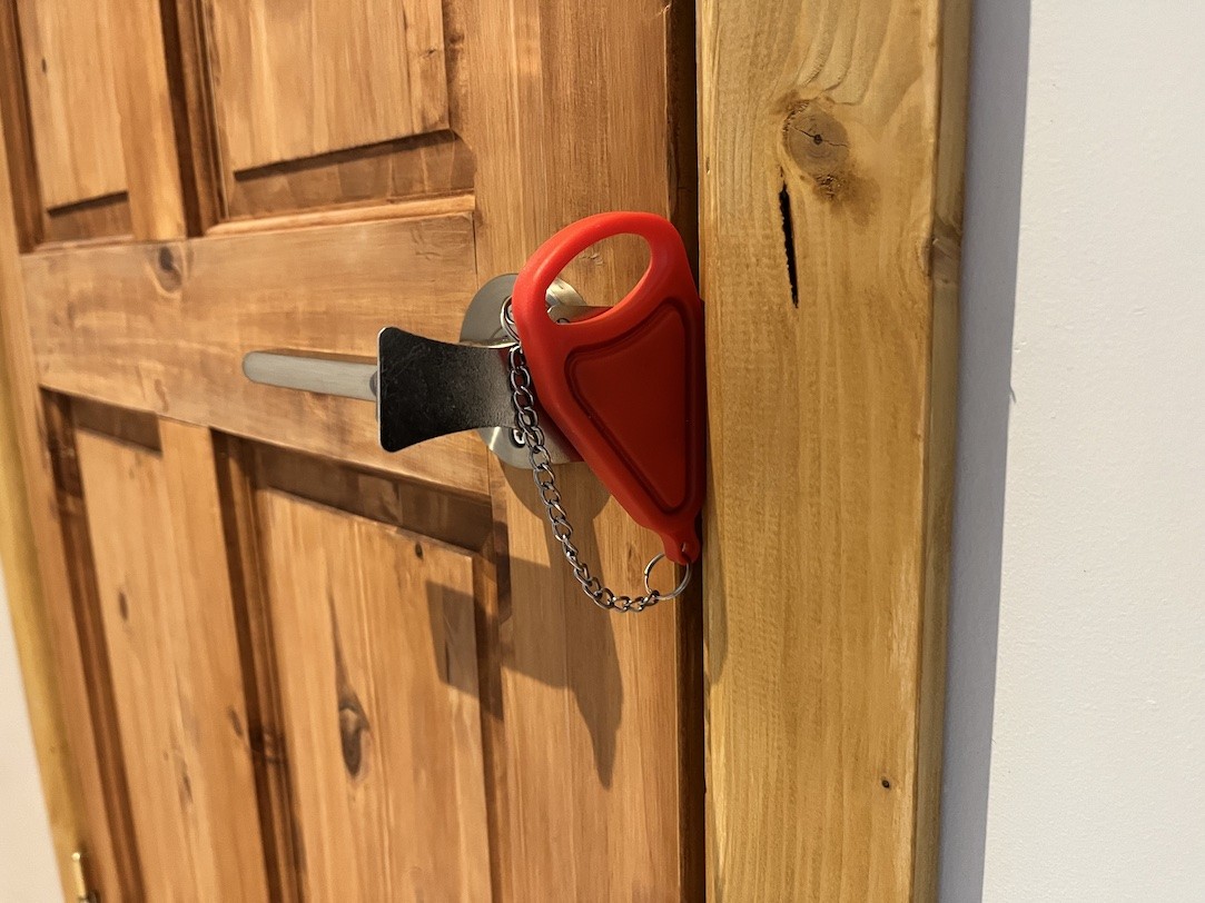 Portable door lock in use on a door.