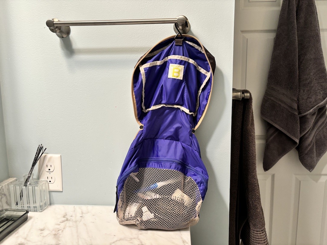 A hanging toiletry bag filled with items in a bathroom.