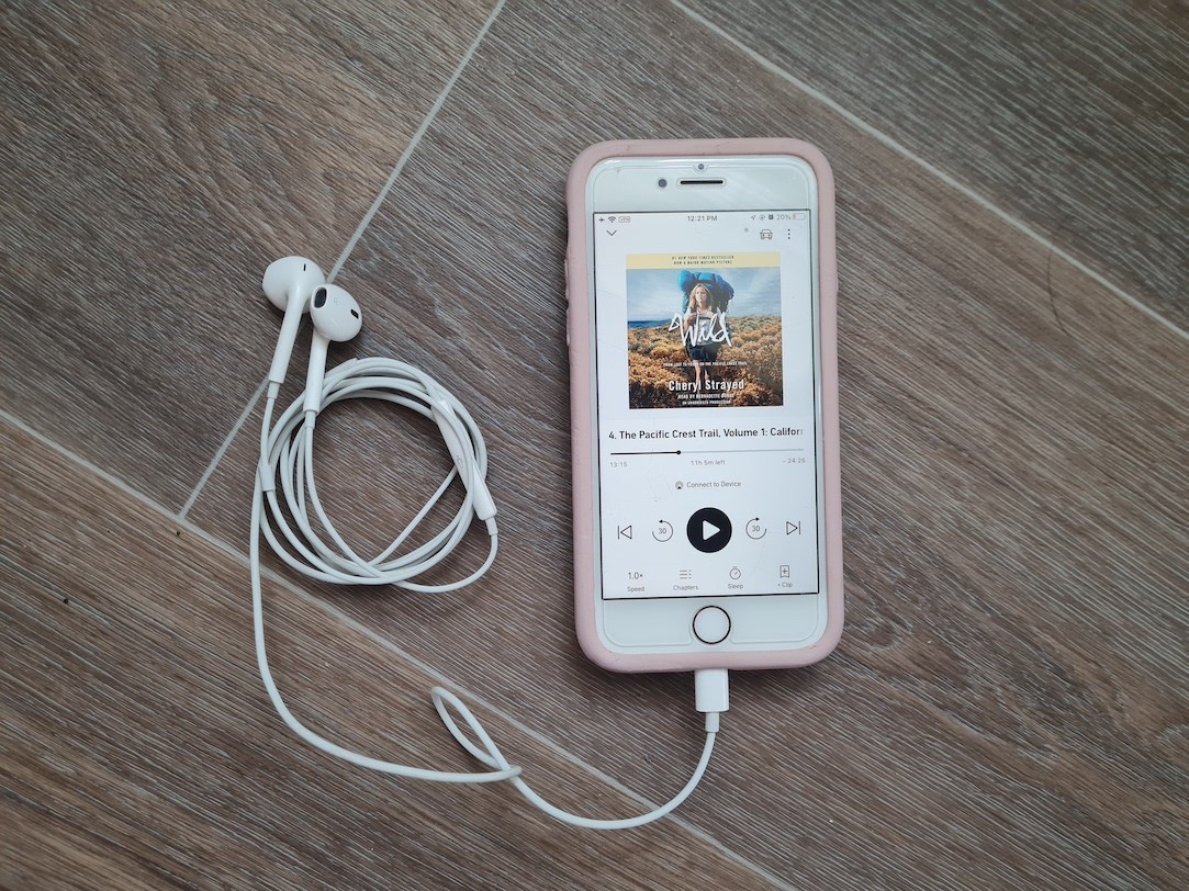An audiobook version of Wild from Lost to Found on the Pacific Coast Trail is paused on chapter four. Headphones are coiled next to the phone. 