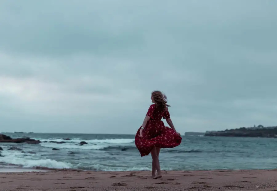 A girl in a red dress walking on a beach