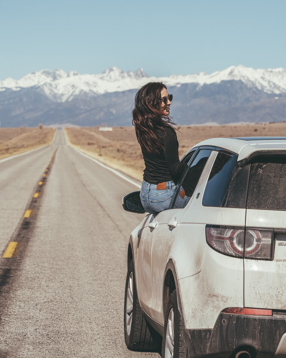 A car driving on a scenic highway with mountains in the background
