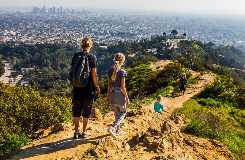 woman and child walking trail along ridge with views of la skyline