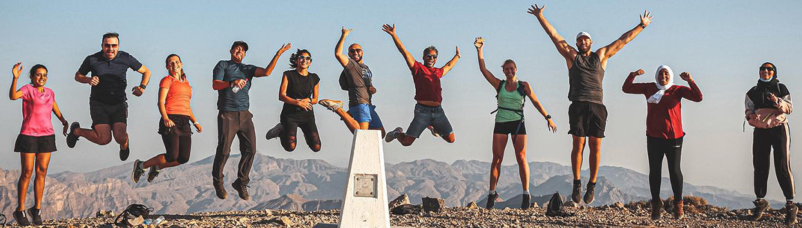 Group of people jumping off a rock cliff into the water