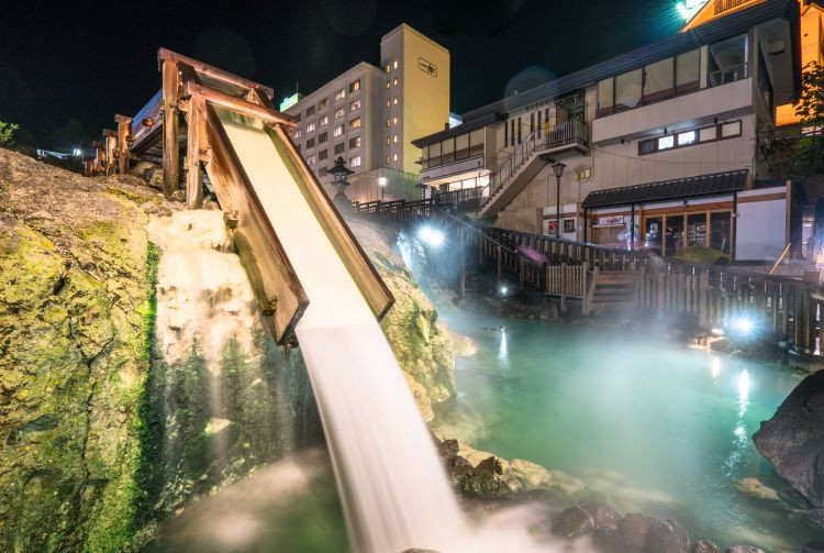 Steaming hot water pours into the emerald green basin.