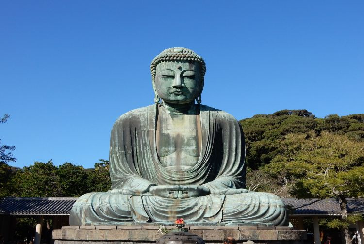 The Great Buddha of Kamakura, a monumental bronze statue, standing serenely amidst lush greenery.