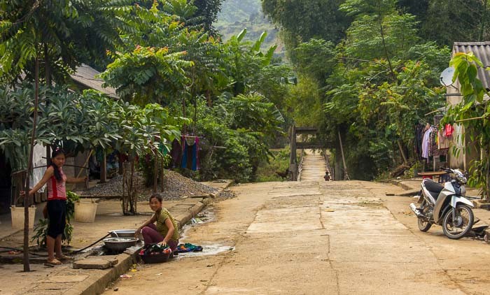 The way into a small town in Ha Giang over a narrow and rusty bridge, emphasizing the rustic charm and accessibility of remote areas.
