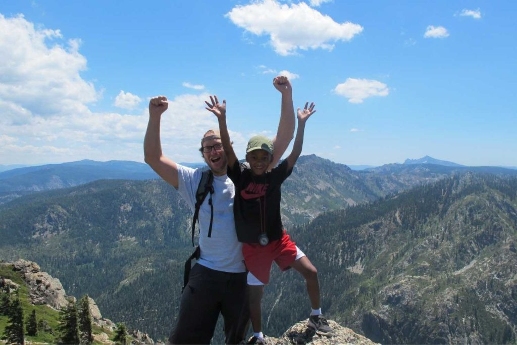 Two happy hikers celebrating atop Eureka Peak in Plumas County, California, under a clear blue sky