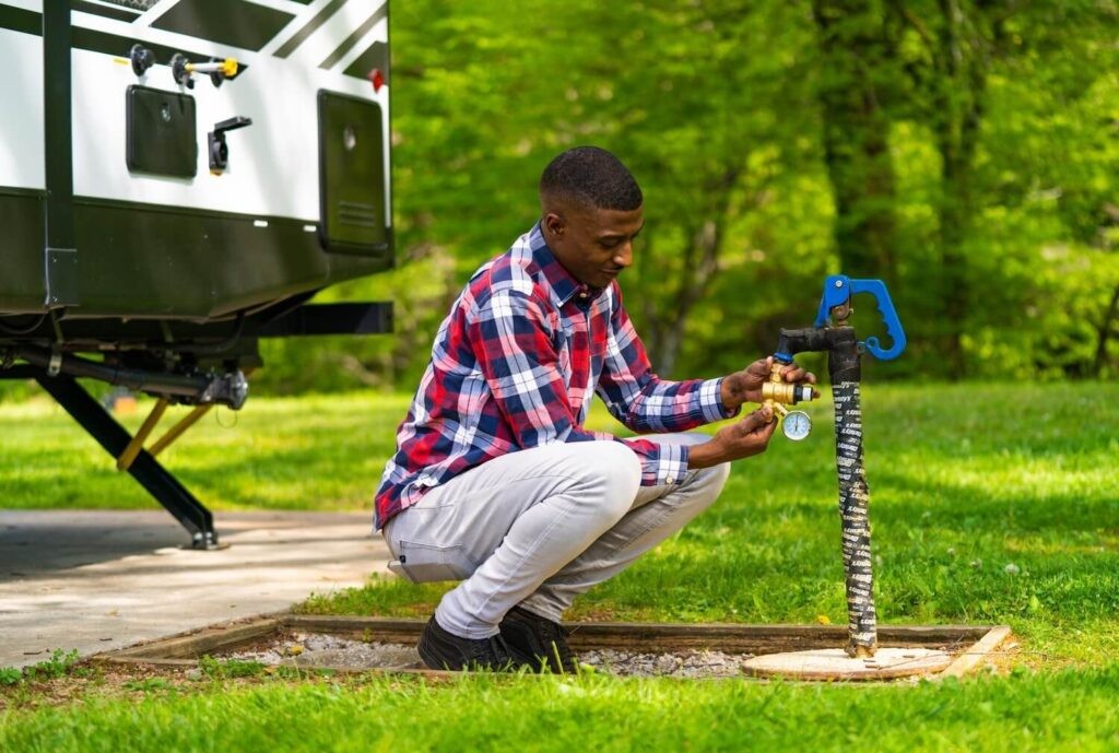 Man hooking up regulator to campground spigot
