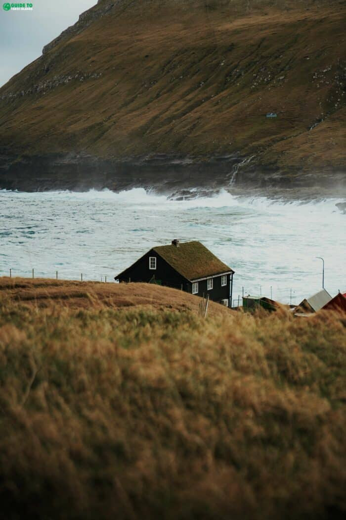 House in front of rough sea in Faroe Islands