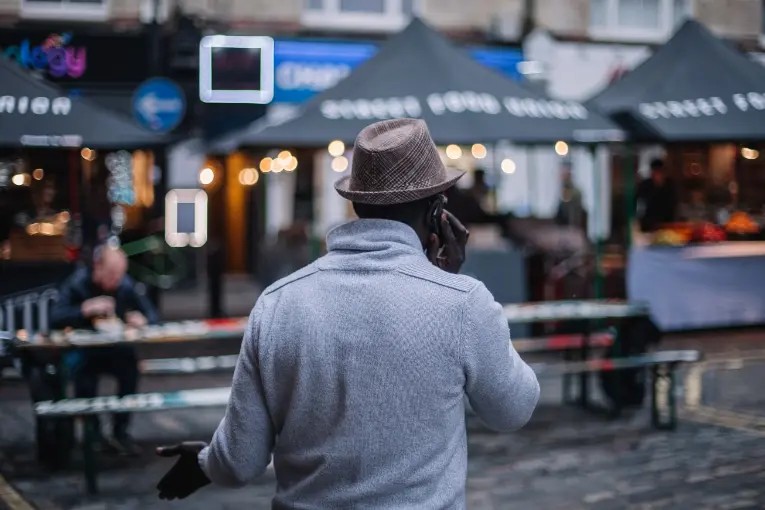 Back of person holding cell phone up to ear while outside