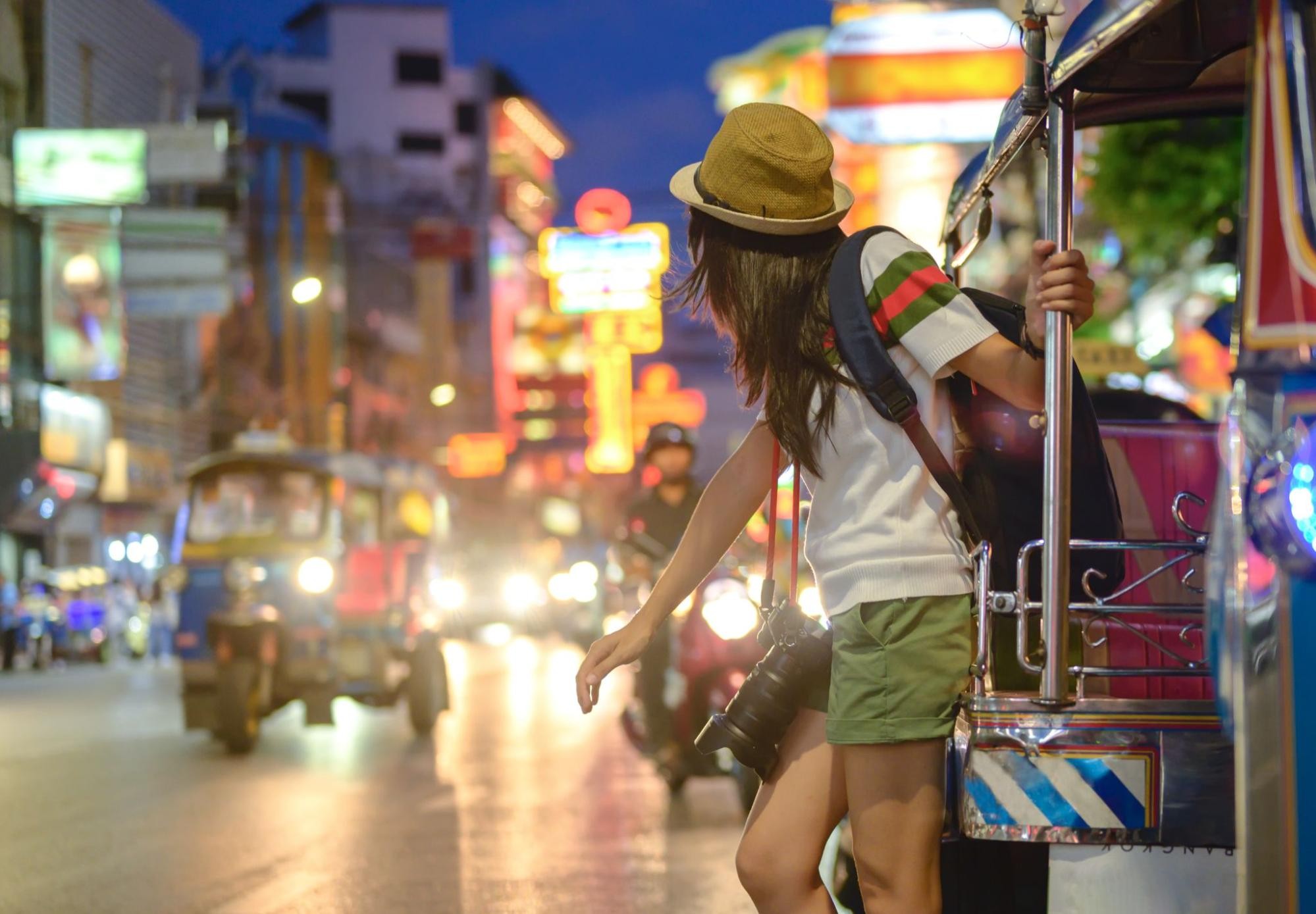 Woman in Thailand, wearing comfortable clothes while hailing a tuk-tuk