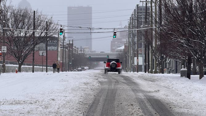 A driver carefully navigates a snow-covered road, demonstrating safe winter driving practices in Indiana.