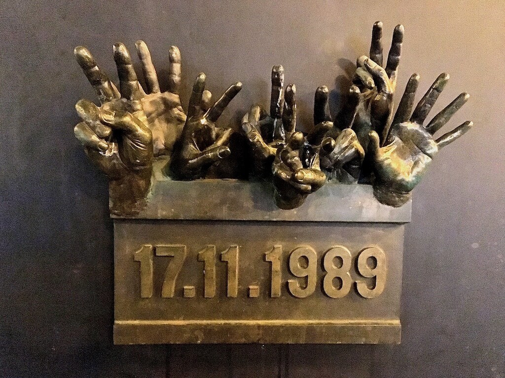 Velvet Revolution Memorial Plaque in Prague of hands hands reaching out and making peace symbols with date of 17.11.1989 beneath