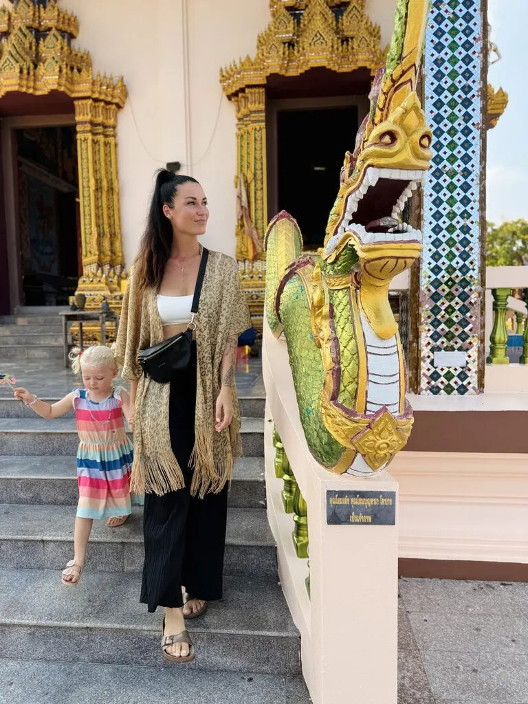 A woman and a child standing on stairs next to a statue.
