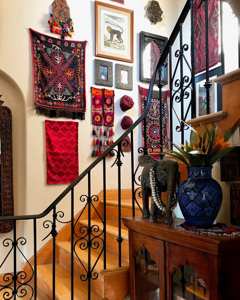 Front entry stairway adorned with vintage textiles and eclectic prints, reflecting the India World Traveler Collection's unique gallery wall