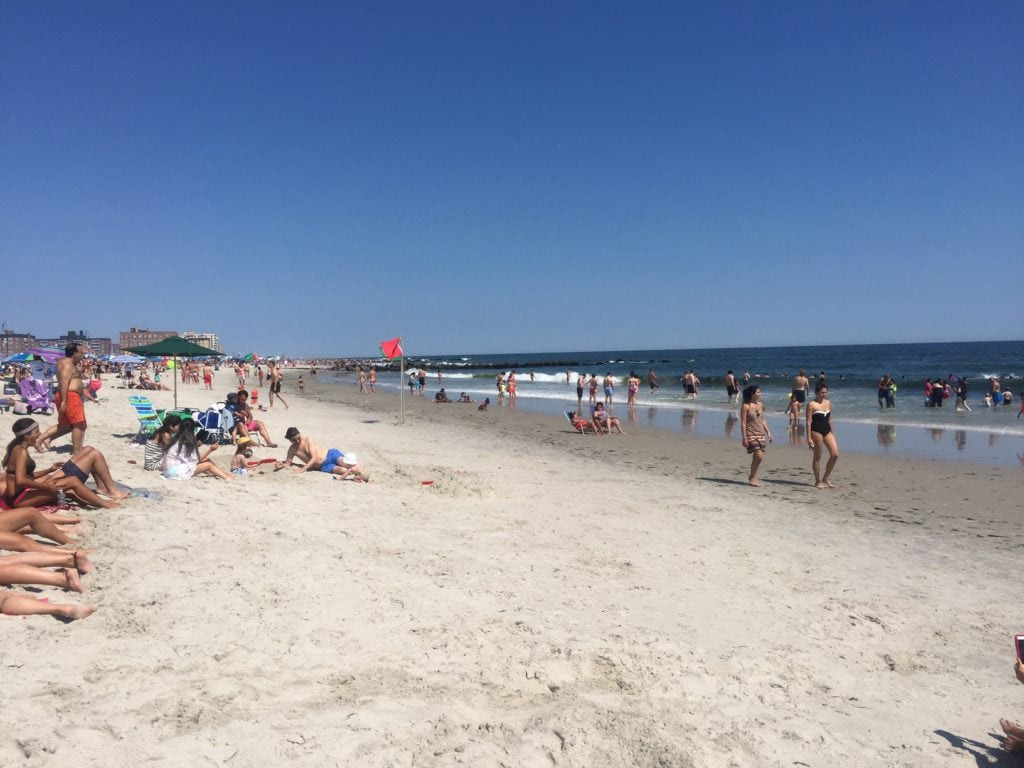 People enjoying a sunny day at Long Beach, New York, with clear skies