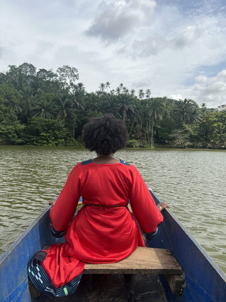 Black woman in a red dress sitting in a canoe in Bini Lagune