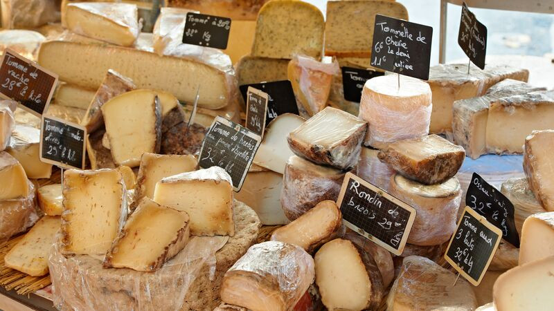 A diverse display of traditional French cheeses at a market in Provence, highlighting France's rich culinary heritage and local produce