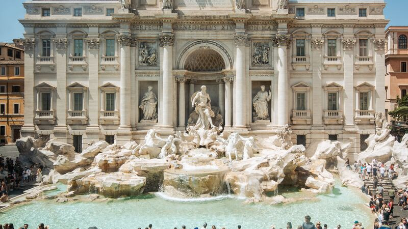 The intricate details of the Trevi Fountain in Rome, with crowds of people surrounding it, showcasing the city's artistic heritage and popular attractions
