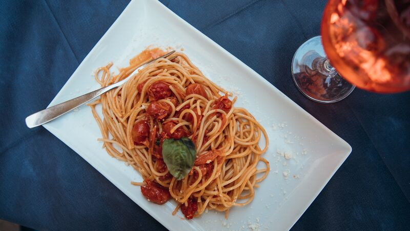 Heaped plate of spaghetti with tomatoes and a glass of wine, representing the simplicity and freshness of Italian cuisine