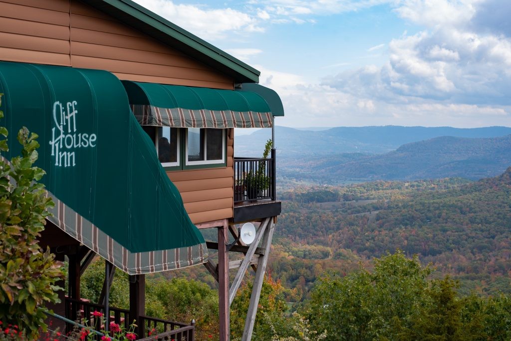 The Cliff House Inn and Restaurant has views of the Arkansas Grand Canyon. In the photo you see the restaurant on the left side hanging out over the canyon. The hills go away into the distance on the right of the photo. 