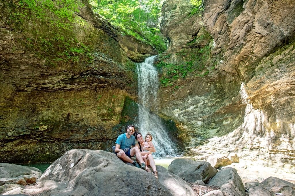 A young man and woman and a child in front of Eden Falls at the Lost Valley Trail near Jasper, Arkansas