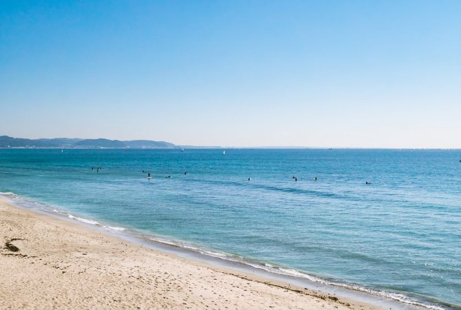 A family enjoys a sunny day at Yuigahama Beach in Kamakura, building sandcastles and playing by the sea.
