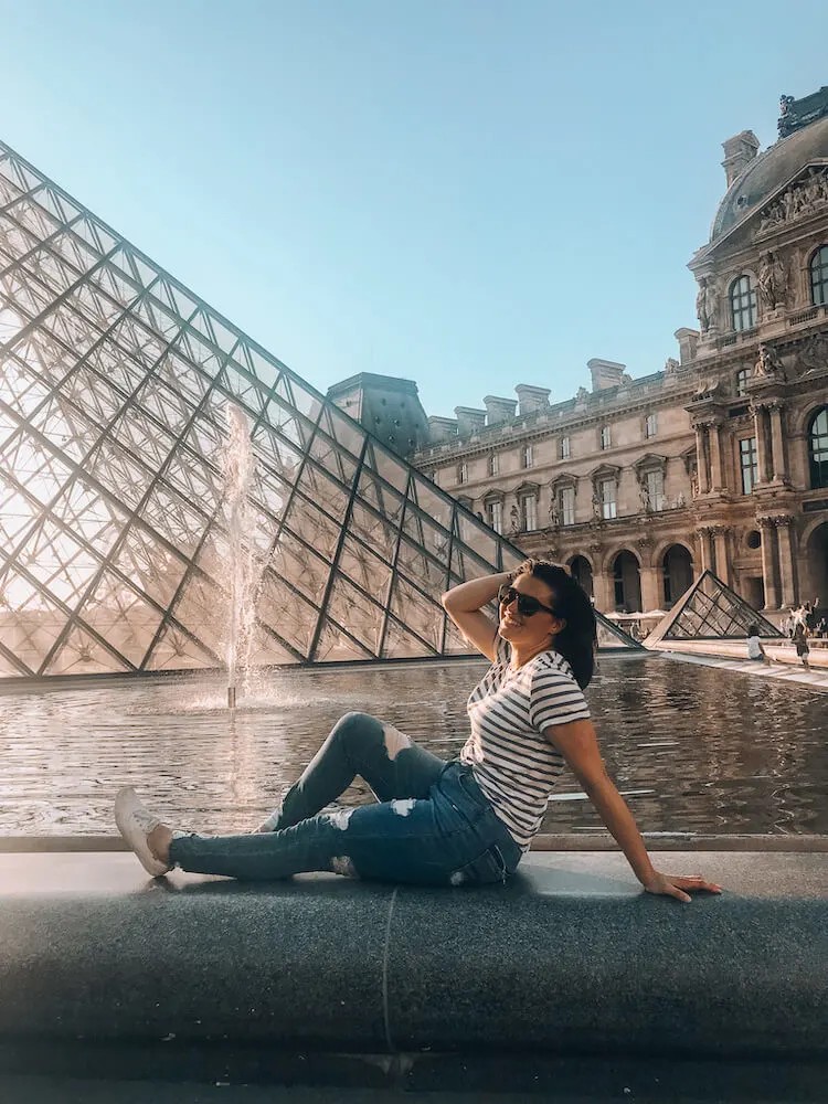 Kat in front of the Louvre. Alt Text: Tourist in front of the Louvre Museum in Paris, a popular spot for photos and visits