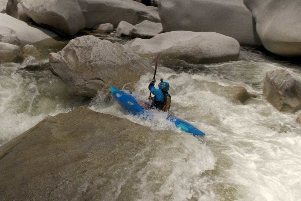 A kayaker navigates the Middle Fork of the Feather River, surrounded by lush greenery and rocky riverbanks
