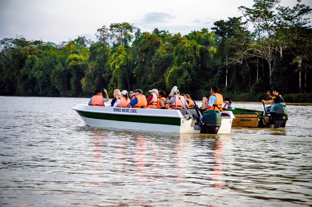 People in life vests riding a boat on Kinabatangan River, Malaysia.