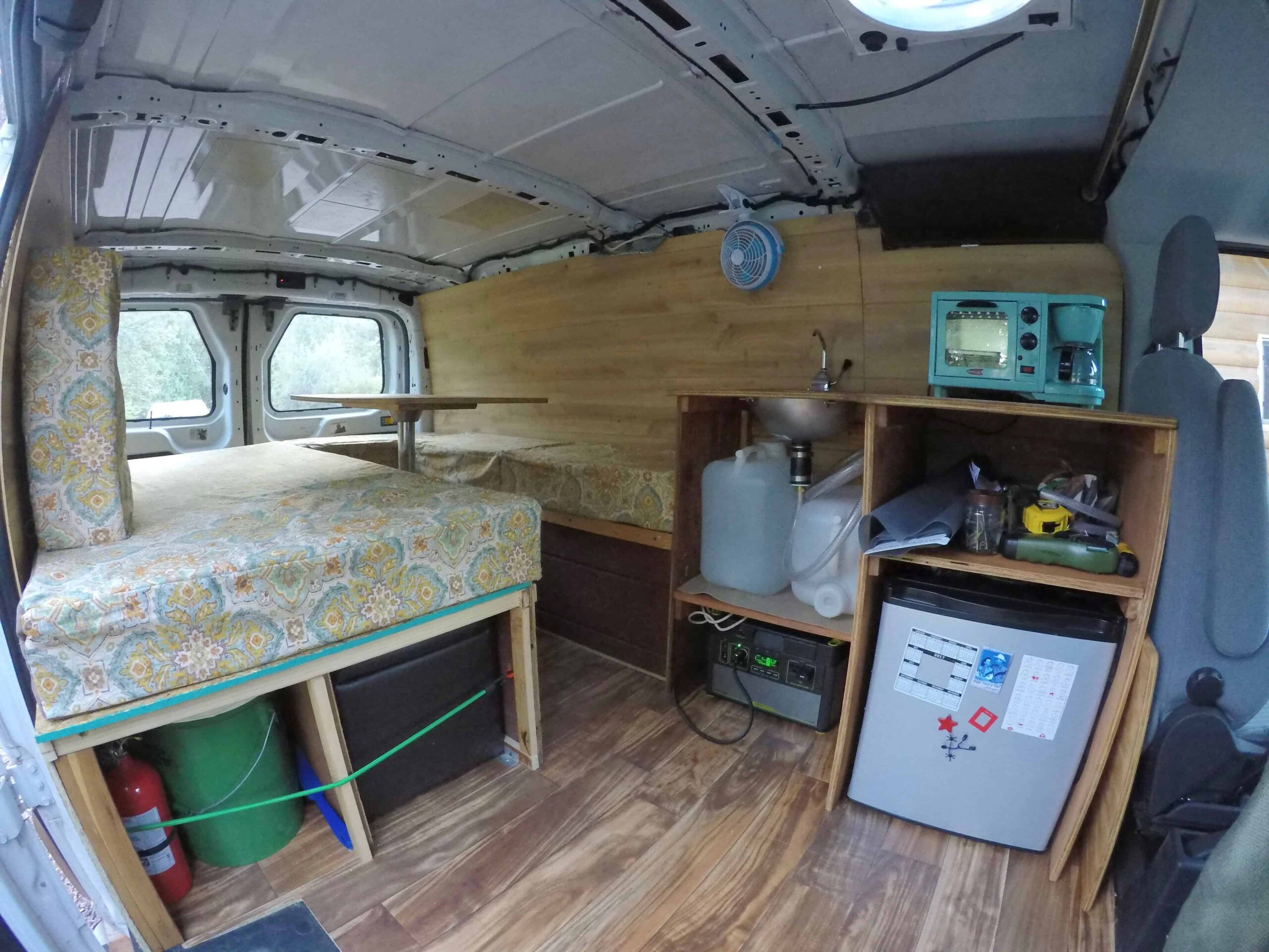 Installed kitchen in a travel van, featuring a fridge, sink, and breakfast center