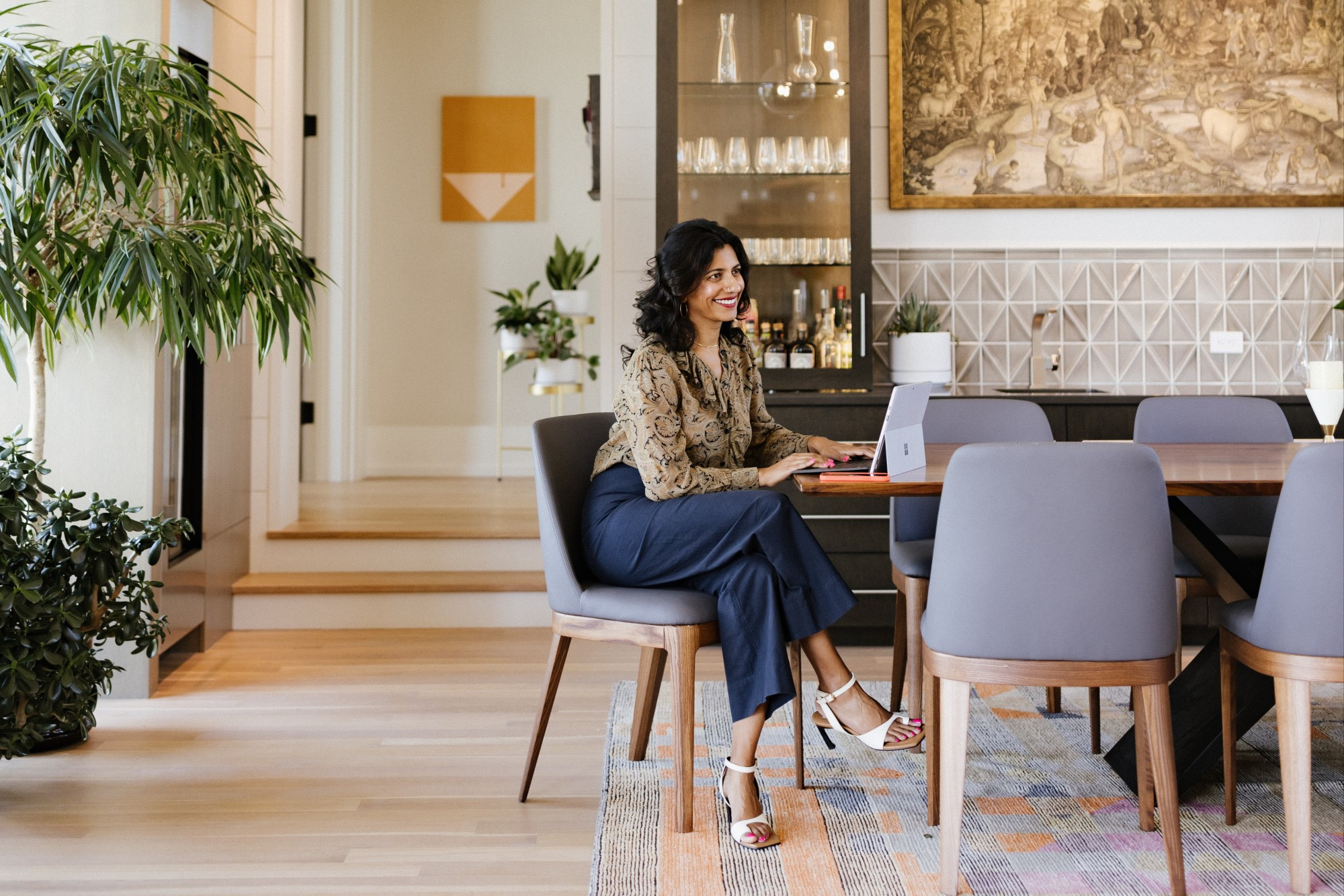 Travel agent Gaya Vinay sitting at a kitchen table with her laptop