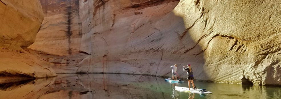 A couple paddleboards through Glen Canyon Recreational Area in Page, Arizona