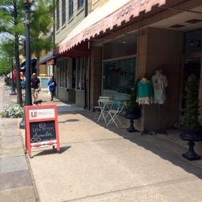 A chalkboard sign on the sidewalk in front of a retail store, promoting shopping in Alabama
