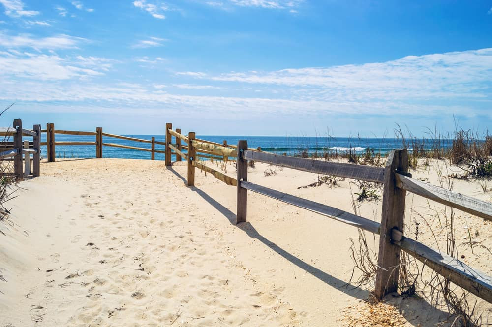 A vibrant beach scene on Long Beach Island, New Jersey, featuring sunbathers, swimmers, and colorful umbrellas along the sandy shore