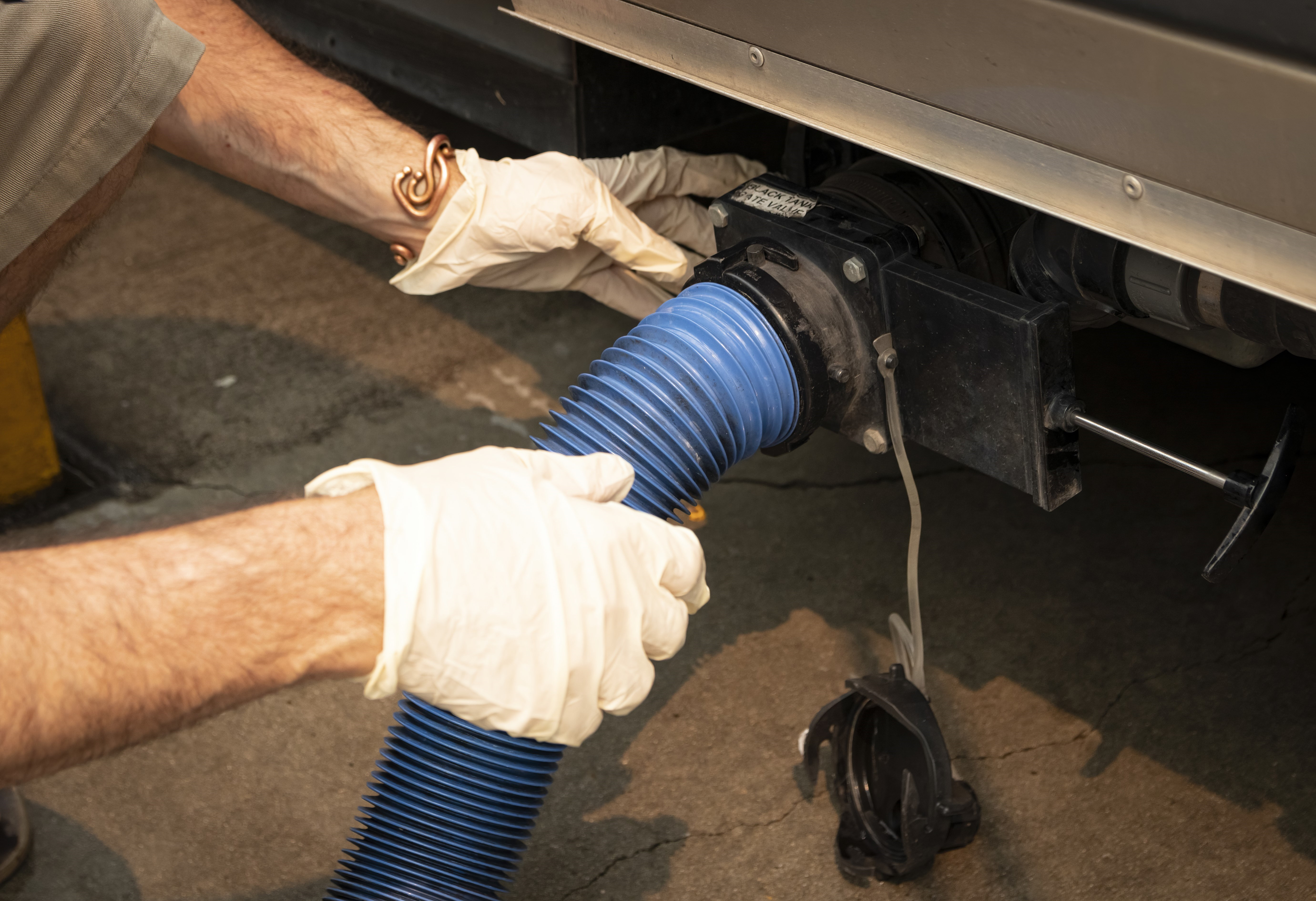 A man's hands connecting hose to RV tank